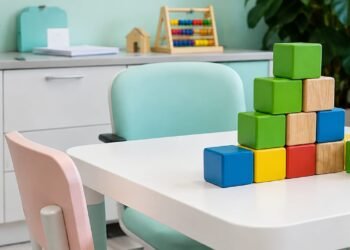Sala de atendimento infantil com mesa, cadeiras e blocos coloridos, representando um ambiente de aprendizagem e intervenção comportamental.