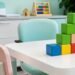 Sala de atendimento infantil com mesa, cadeiras e blocos coloridos, representando um ambiente de aprendizagem e intervenção comportamental.